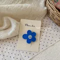 Vista detallada de una pinza de pelo de flor azul mate con centro floral en tarjeta - Pinza de Flor Azul Oscuro