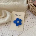 Vista detallada de una pinza de pelo de flor azul mate con centro floral en tarjeta - Pinza de Flor Azul Oscuro