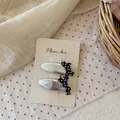 Dettaglio di due fermagli per capelli argentati con fiocchi a pois neri e bianchi su carta - Fiocco a Pois Argento Metallizzato