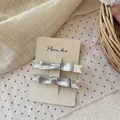 Detalle de dos pinzas para el cabello con lazo plateado en tarjeta de exhibición - Lazo de Doble Capa Plateado Metálico