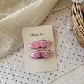 Primer plano de dos horquillas metálicas rosas con lazos en una tarjeta de exhibición - Lazo de Cinta Rojo Púrpura Metálico