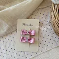 Detailaufnahme rosa Schleifen-Haarspangen mit Metallic-Finish auf Display-Karte - Purpurrot Metallic Schleife