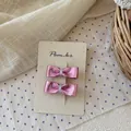 Detalle de pinzas para el cabello con lazo rosa y acabado metálico en tarjeta decorativa - Lazo Rojo Púrpura Metálico