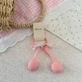 Close-up of pink cherry-style elastic hair tie with floral bow and fabric tag on lace - Orange Cherry Hair Tie