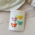 Detailed view of four colorful butterfly metal hair clips on a white display card - Yellow And Dark Pink And Green And Orange