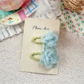 Close-up of light blue mesh flower hair clips on beige display card with floral background - Green Flower Hair Clip
