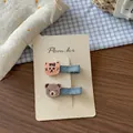 Dettaglio di fermagli ricamati con tigre e orso su denim con sfondo a quadretti blu - Stile Gatto + Orso