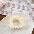 Detail of cream ballet lace hair scrunchie with satin texture and white faux pearl accent - Beige