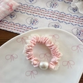 Detailed view of pink lace scrunchie featuring a large central pearl on a white ceramic tray - Pink
