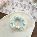 Close-up of ballet-style light blue lace scrunchie with white frills and large faux pearl - Green