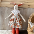 Makroaufnahme einer handgefertigten Leinenhasenpuppe mit Blumenkleid und Spitzenkragen - Oranges Blumenmuster Stil