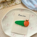 Detail of cute green embroidered hair clip with orange fruit design on display card - Green Apple Hair Clip