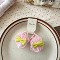 Détail de chouchous fleurs en dentelle rose avec nœuds verts sur plateau céramique - Hortensias Roses
