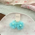 Détail de chouchous fleurs en tulle bleu avec centre en peluche sur une assiette blanche - Bleu