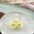 Détail de chouchous fleurs en tulle jaune avec centre en peluche sur plat céramique - Jaune