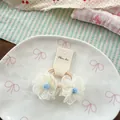 Dettaglio di due elastici per capelli a fiore in rete bianca con centro blu su piatto - Bianco Sporco