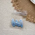 Close-up of three blue and white checkered hair clips in transparent plastic packaging - Blue Plaid Style