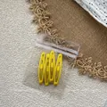 Set of four yellow matte teardrop hair clips in transparent packaging on beige background - Yellow Style / Set of 4