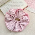 Vista dettagliata di un elastico per capelli oversize a righe rosa su sfondo beige - Righe Rosa