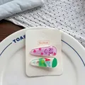 Detailansicht von zwei süßen Acryl-Haarspangen mit Erdbeer- und Getränkemotiven für Kinder - AD Calcium Milch Stil