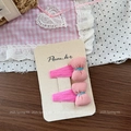 Gros plan de barrettes à nœuds roses avec coutures bleues sur une carte de marque - Pince à Cheveux Noeud Rose Vif