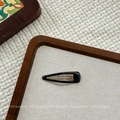 Close-up of a minimalist glossy black teardrop BB hair clip on a textured wooden tray - Black Waterdrop BB Clip (NK2084-10)