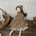 Detail showing a handmade fabric doll with brown plaid dress and yarn braids on wooden table - Yellow Checkered Style