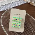 Details von grünen Gingham-Haarspangen mit Herzstickerei auf einer Displaykarte - Grüne Serie