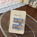 Close-up of handmade floral embroidery hair clips on blue checkered fabric base - Blue Series