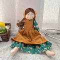 Handgefertigte Stoffpuppe in gelber Schürze mit geblümtem Kleid und braunen Zöpfen - Grünes Blumenmuster