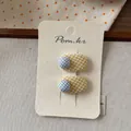 Dettaglio macro di fermagli per capelli in tessuto a scacchi gialli e blu su carta - Giallo