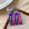 Detalle de 4 pinzas para el cabello en azul neón y rosa dentro de su empaque minorista - Azul y Rojo Rosa