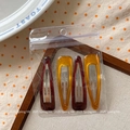 Macro detail of 4-piece resin teardrop hair clips in tortoiseshell and amber in a bag - Dark Red and Yellow