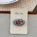 Detail der handgefertigten Eichhörnchen- und Erdbeerstickerei auf Denim-Haarspange - Erdbeere-Eichhörnchen-Stil