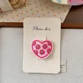 Detail einer herzförmigen Stickerei mit Blumenmustern auf einer Präsentationskarte - Rosenrosa