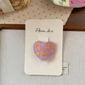 Close-up of purple heart-shaped hair clip with yellow floral embroidery on card - Purple