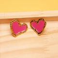 Close-up of golden heart earrings with pink enamel inlay and hammered texture on wood - Pink