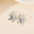 Polished silver stainless steel hoop earrings with 3D star charms on a neutral background - Hollow Star Style / Steel