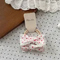 Detail von roten Polka-Dot-Haarschleifen mit weißer Spitze auf einer Displaykarte - Schleife Punkte Scrunchie