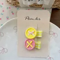 Detail of sweet button hair clips with ribbons on display card and ceramic plate - Yellow + Pink
