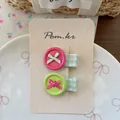 Dettaglio di fermagli a bottone rosa e verdi con fiocchi su carta display in una ciotola - Rosso Rosa e Verde