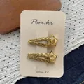 Detailed view of two gold metal hair clips with woven texture and polished star accents - Gold Star Hair Clips