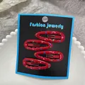 Dettaglio di quattro fermagli per capelli in metallo rosso a pois colorati su carta - Rosso a pois