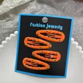 Close-up of 4pcs orange polka dot hair clips for girls on black jewelry card display - Orange Polka Dot