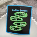 Close-up of four green polka dot snap hair clips on a jewelry card display - Green Polka Dot