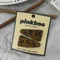 Dettaglio di fermagli per capelli leopardati con texture opaca e cuciture nere sottili - Stile Solido Triangolo Scuro