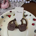 Gros plan sur les élastiques à cheveux ours en daim marron sur une assiette déco - Ours brun