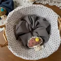 Dettaglio di uno scrunchie grigio con ciondolo a fungo fatto a mano e motivi floreali - Grigio