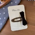 Nahaufnahme einer braunen Samt-Schleifen-Haarspange auf einer Display-Karte aus Karton - Braun