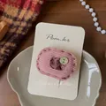 Detail van roze corduroy haarspeld met vintage bronzen knoop op een displaykaartje - Roze Bloemen Knoop